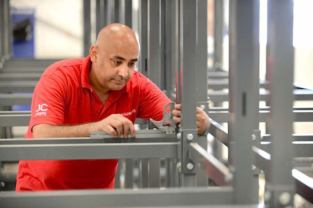 JC Metalworks 6065 man checking for the precision manufacture and assembly of a metal stand