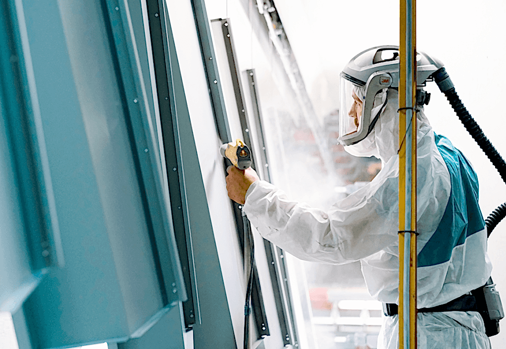 quality JC Metalworks employee spraying a powder coating